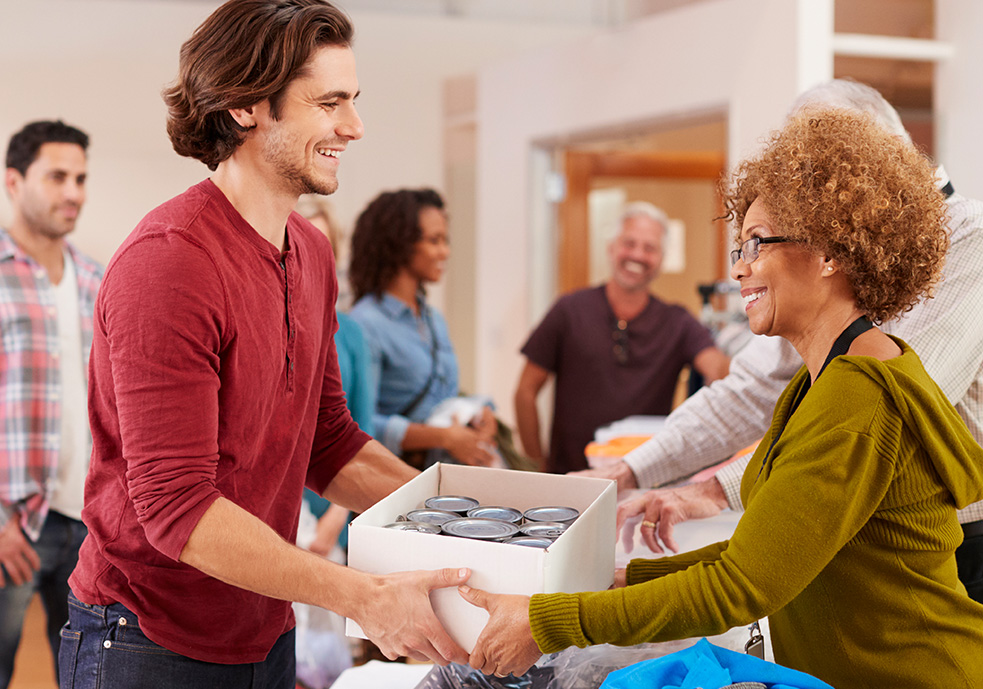 Woman handing out boxes of canned goods to a man